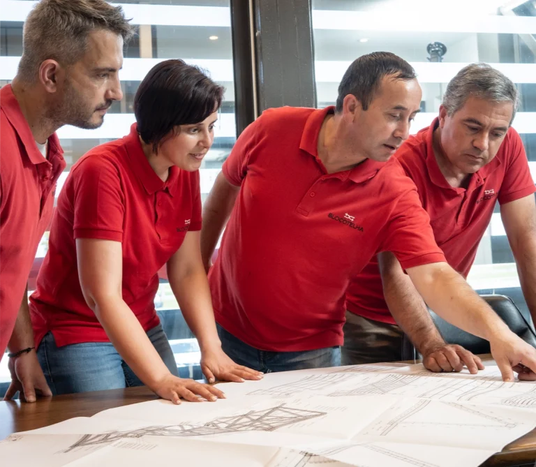 Four co-workers reviewing a blueprint at the factory.